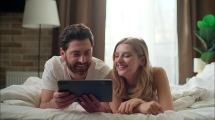 Laughing Caucasian family married couple holding tablet in bedroom love cheerful boyfriend girlfriend typing device woman purchasing goods app Internet man remote shopping together morning cyberspace - Powered by Adobe
