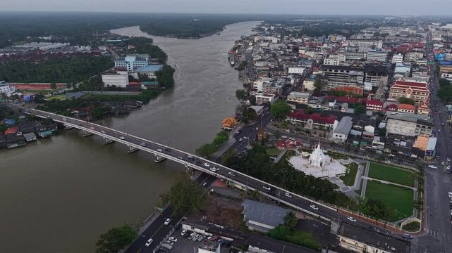Aerial view of Surat Thani, Thailand, featuring the City Pillar Shrine, Tapi River, and city bridges under a vast sky at dusk.