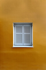 Closed Shutter Window on Yellow Wall