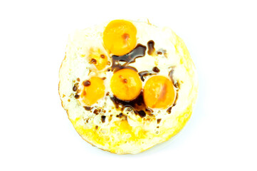 Small quantity oil fried eggs in flying pan with soy sauce, egg whites are set and yolk sunny side up, in a white dish isolated on white background top view flat lay stack