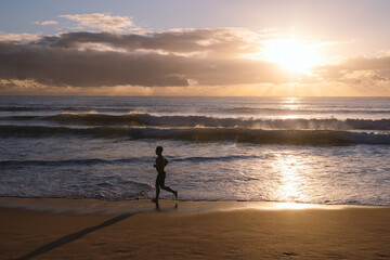 Athlete running on the beach at sunrise
