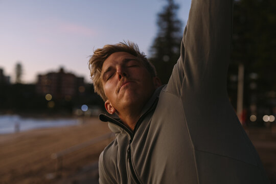 oung man stretching on beach at sunrise at manly beach