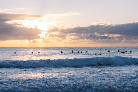 Surfers waiting for waves at sunrise on scenic coastline