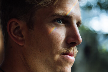 Rainbow reflecting on young man's face creating colorful effect