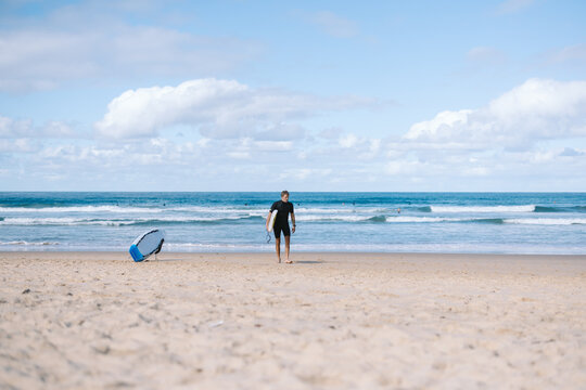 Surfer carrying surfboard walking on the beach