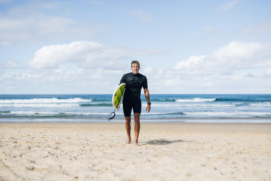 Surfer is walking out of the ocean after surfing some waves