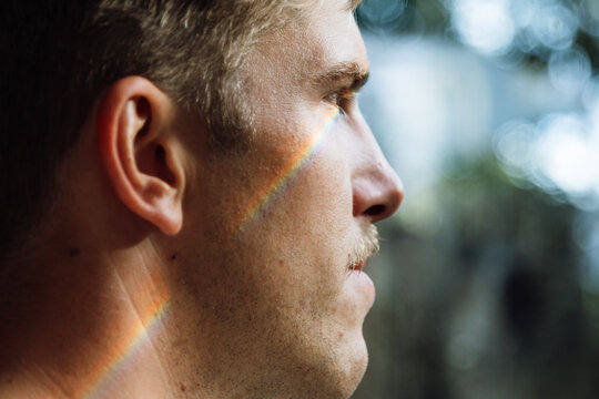 Rainbow reflecting on man's face creating colorful effect