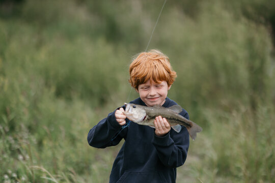 Young fisherman grins while showing off his catch outdoors