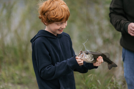 Young boy holds fish proudly after a successful fishing trip