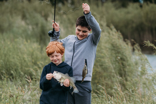Siblings enjoy nature while proudly holding their fish catch