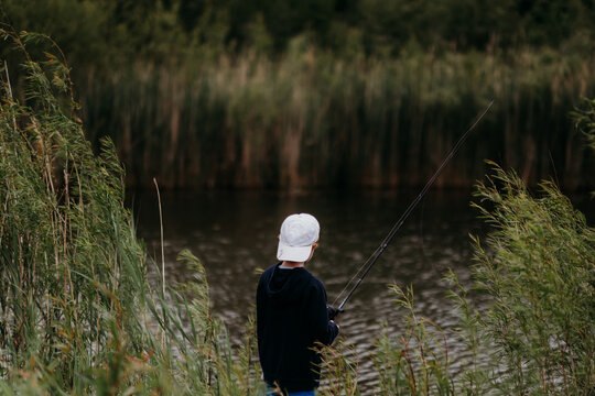 Boy fishing in pond surrounded by natural greenery