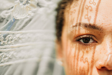 Close-up of woman's eye with lace shadow patterns on her skin