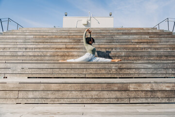 Woman doing full split on outdoor wooden bleacher steps