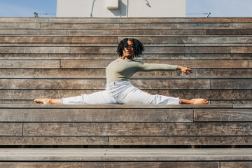 Woman performs a split on wooden bleachers, arm extended forward