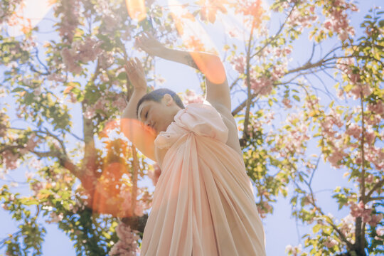 Woman in peach dress dancing under blooming cherry trees
