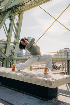 Woman in yoga pose on wooden platform in urban outdoor setting