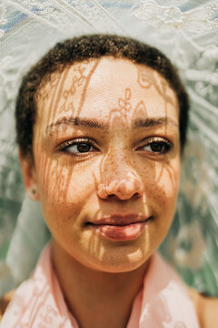 Woman smiling softly with lace shadow patterns on her face