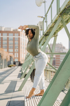 Woman standing barefoot on bench in a graceful dance pose