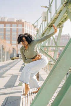 Woman posing dynamically on bench near green steel beams