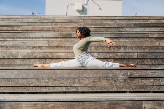 Woman in side split pose on tiered wooden bleacher steps