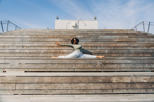 Woman performing a split on wooden bleacher stairs outdoors