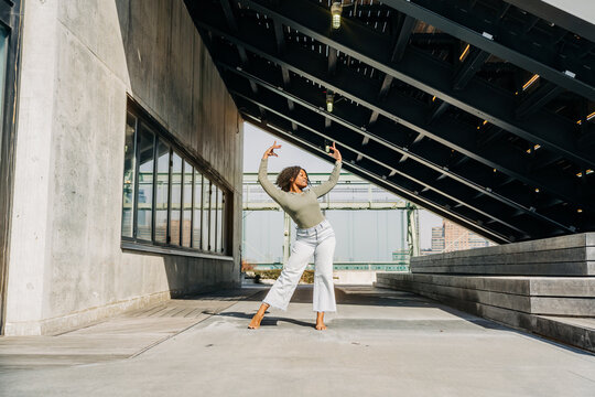 Dancer strikes elegant pose beneath steel canopy in urban setting