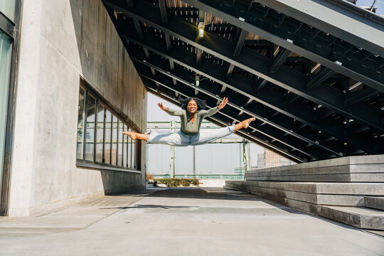 Dancer performs mid-air split under geometric steel canopy - Powered by Adobe