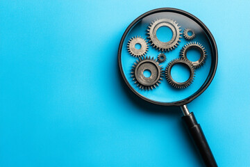 Magnifying glass reveals intricate gear mechanism on blue background