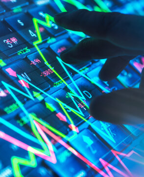 Hand interacting with a digital stock market graph on a screen