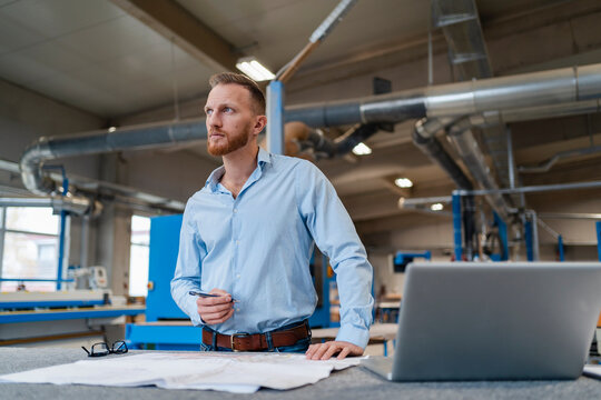 Portrait of carpenter examining documents in production hall