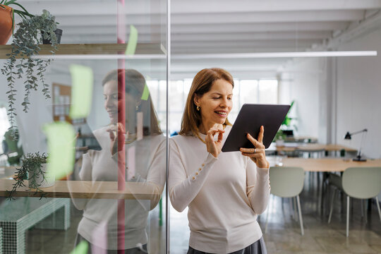 Businesswoman in a modern office holding a digital tablet and smiling