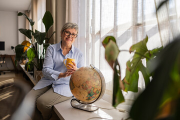 Woman enjoying coffee by a globe at home