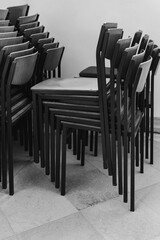 Stacked wooden chairs create a minimalist art piece in the quiet corner of a bustling cafe at midday