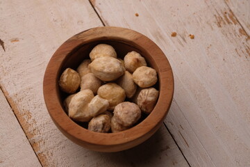 Candlenuts are the seeds of the Aleurites moluccanus tree. Candlenuts in a wooden bowl.