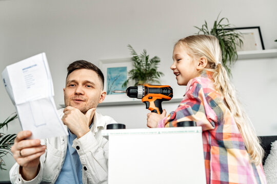 Father and daughter reading instructions and assembling furniture at home