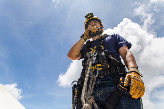 Engineer inspecting wind turbine nacelle with safety gear and walkie talkie outdoors