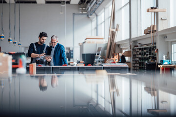 Engineer and craftsman discussing a project in a workshop
