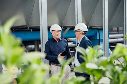 Engineers discussing a project outdoors wearing hard hats