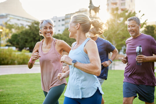 Mature group of men and women running together at park during sunset