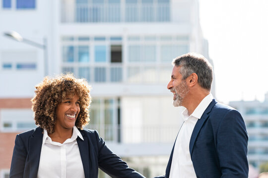 Cheerful business people looking at each other while standing outdoors