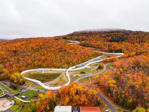 Aerial view of the Olympic Bobsled Run at Mount Van Hoevenberg in Lake Placid, New York, surrounded by autumn foliage.