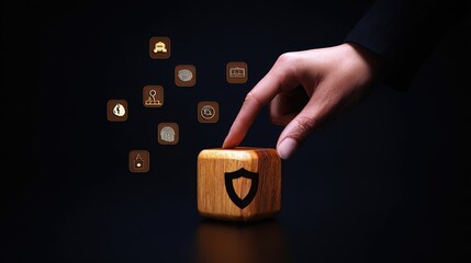 In a low-light setting, a hand emerging from a dark sleeve interacts with a shiny wooden block featuring various security icons, suggesting themes of protection and technology