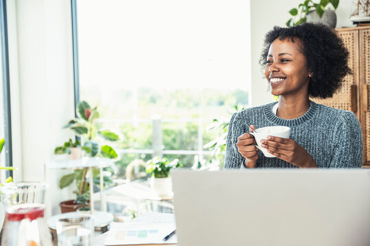 Young businesswoman smiling while having coffee at home