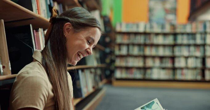 Happy woman, laughing or reading with book in library for comedy story, funny joke or humor. Female person, student or studying with smile or novel on floor for comic, genre or amusement by bookshelf