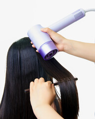 Makeup artist using comb and hair dryer to blow dry girl's hair