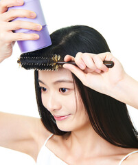 Asian girl using comb and hair dryer to blow her hair