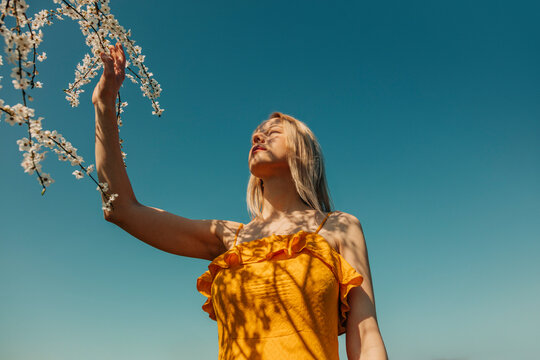 Woman in yellow dress enjoying springtime under cherry blossoms