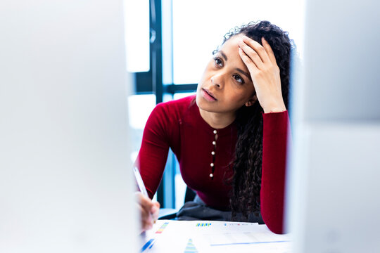 Tired businesswoman with head in hand at coworking space