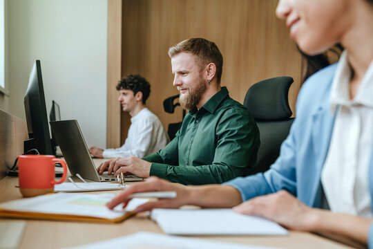 Colleagues working together in a modern office setting with laptops