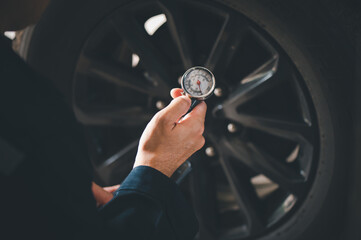 Mechanic holding pressure gauge for car tyre pressure measurement